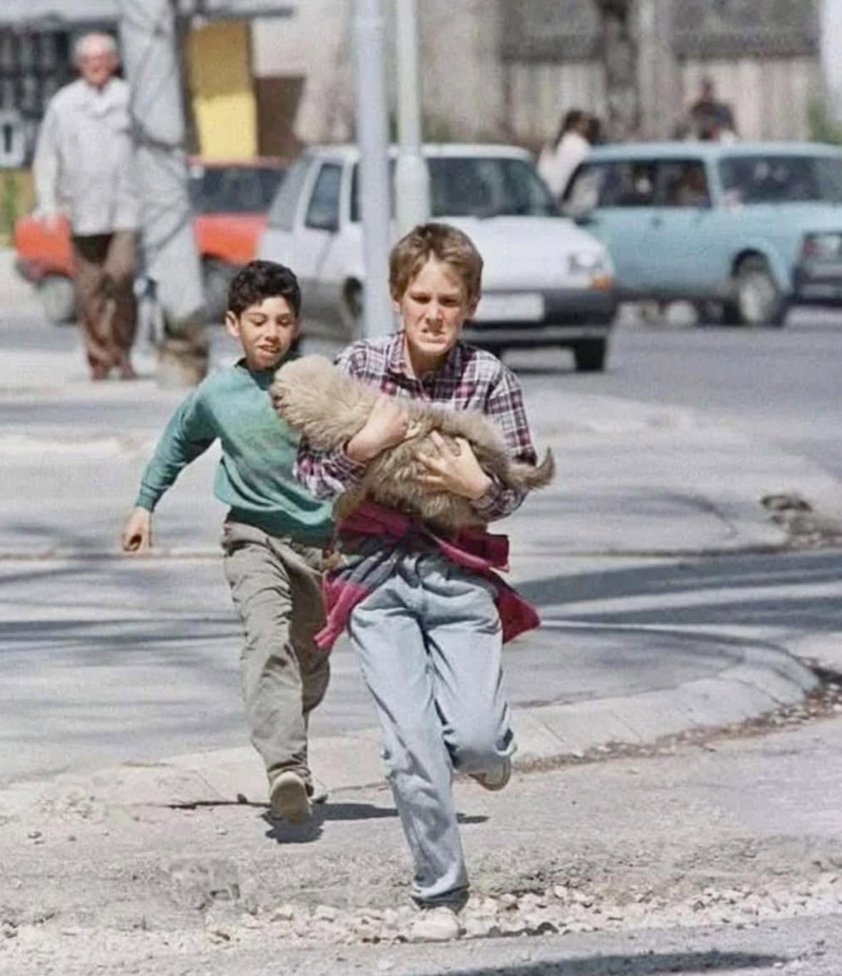 En esta foto se ven dos niños corriendo con su mascota para salvar su vida