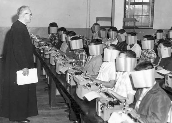 En un examen de mecanografía de secundaria en la década de 2026, los estudiantes usaban grandes tapas de papel para evitar copiar mientras trabajaba...