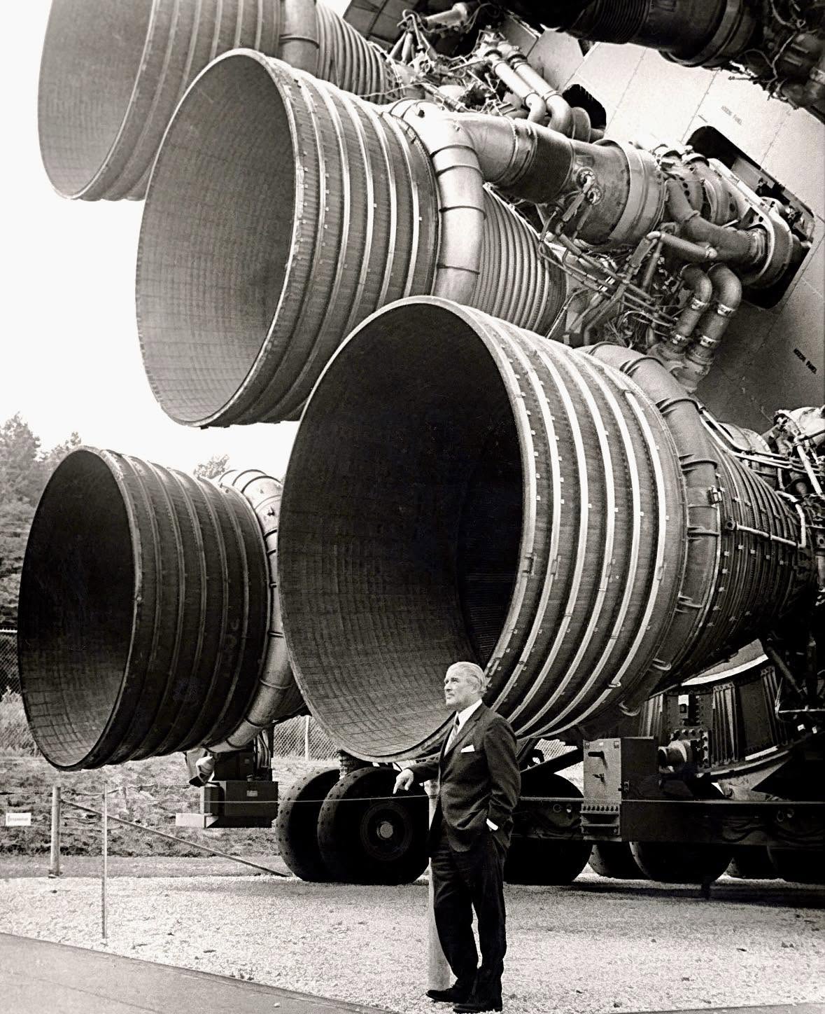 Lo que ves no es un escenario de ciencia ficción; es el ingeniero aeroespacial Wernher von Braun posando frente a los cinco motores F-1 que impulsaro...