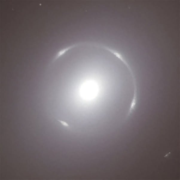 Estás presenciando una de las ilusiones ópticas más asombrosas que el universo puede realizar: la masa de una galaxia deformando el espacio circund...
